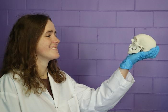 Image: Researcher Elizabeth Diederichs holding a miniature skull that was 3D-printed using the new material (Photo courtesy of University of Waterloo)